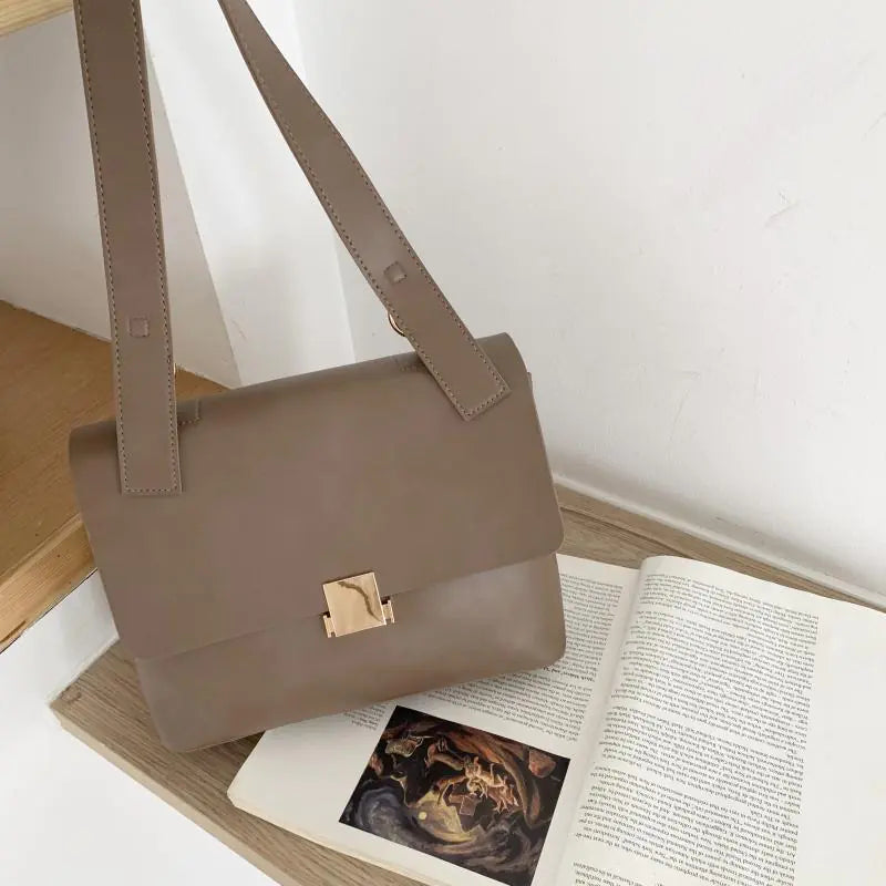 Vintage shoulder bag for women, large capacity crossbody in neutral color on a wooden shelf.