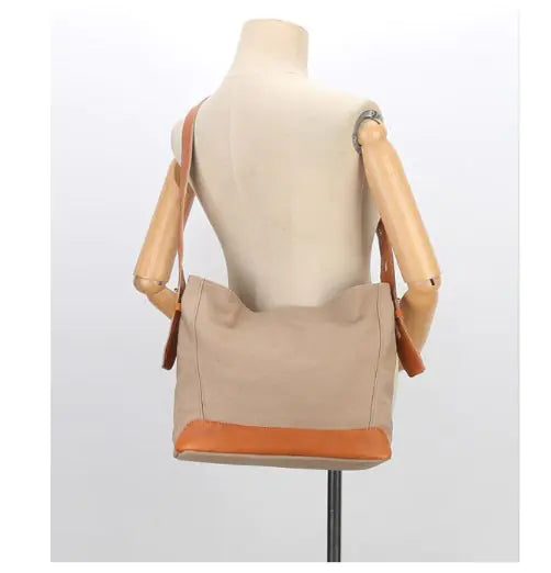 Versatile canvas shoulder and crossbody bag, featuring a durable beige exterior with stylish orange accents.