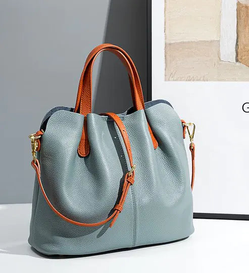 Genuine leather tote bag in light blue with orange straps, showcasing a modern design for stylish women.