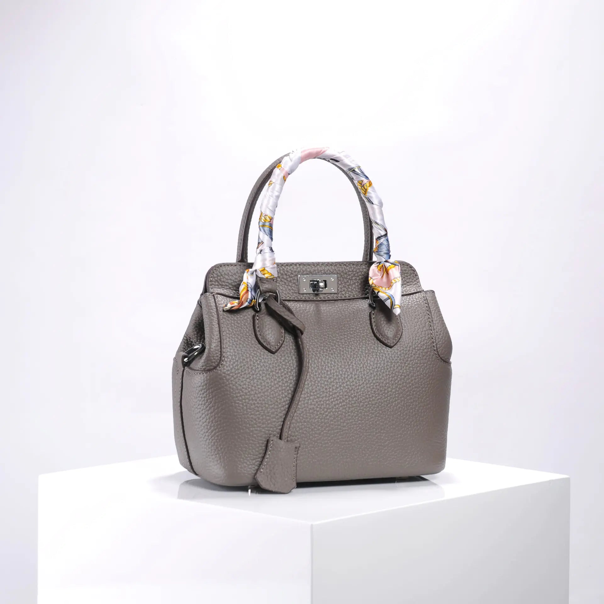 Elegant gray handbag with patterned scarf handles, crafted from premium leather for a luxurious touch.