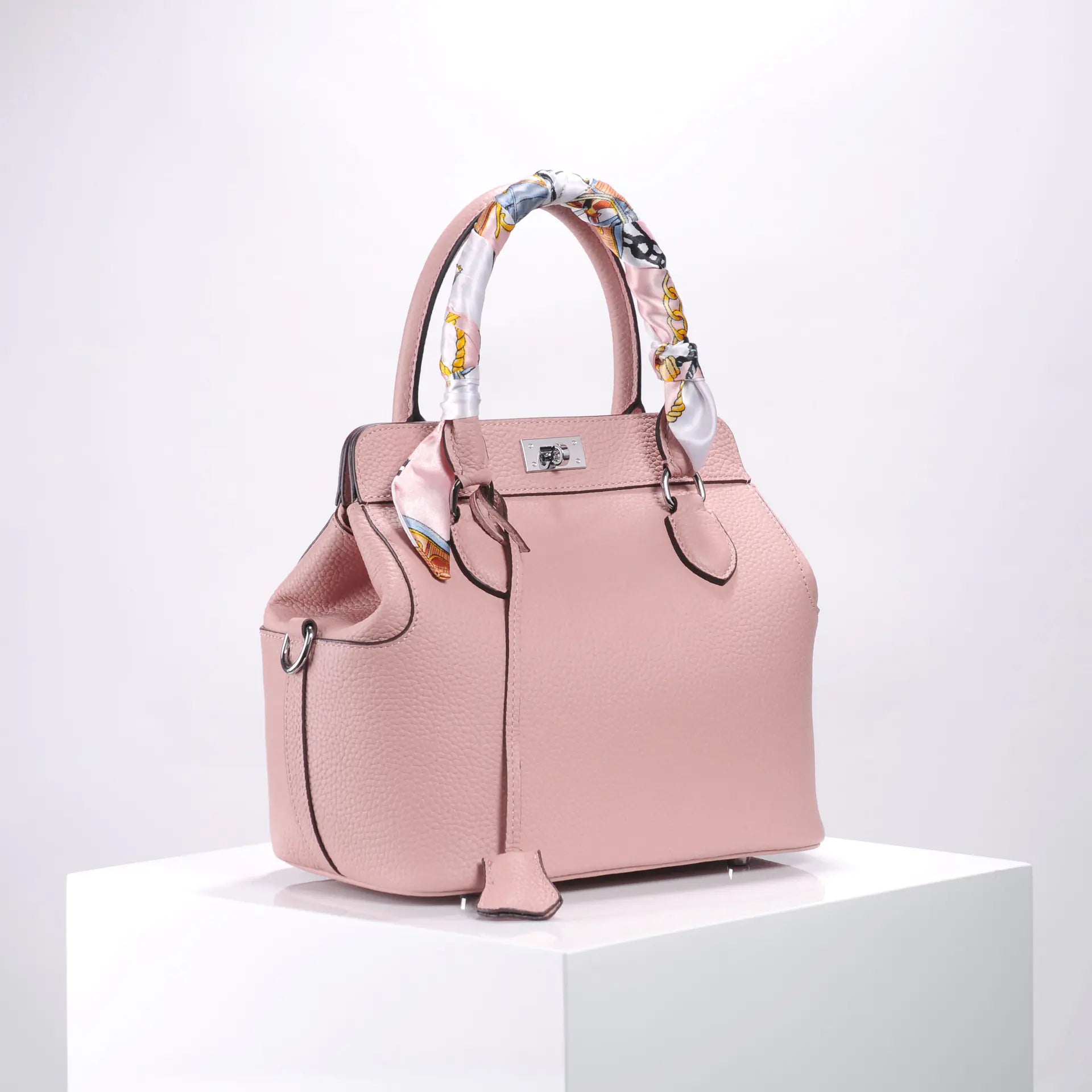 Stylish pink handbag with decorative scarf handles, perfect for elevating your fashion.