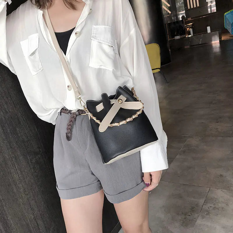 Autumn women's bag featuring butterfly lock chain design, styled with a casual outfit in a modern setting.