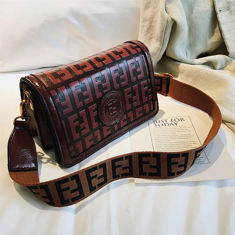 Stylish vintage shoulder crossbody bag in brown with logo detailing and a quality strap on a neutral background.