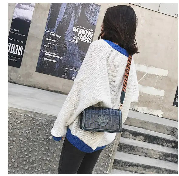 Woman wearing a cozy oversized sweater with a retro style mini shoulder bag in an urban setting.