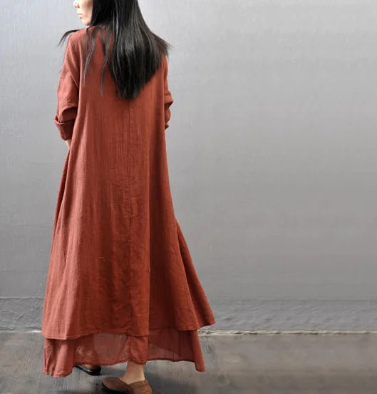 Back view of a woman wearing a rust-colored two-piece long dress with loose sleeves, showcasing its flowy design.