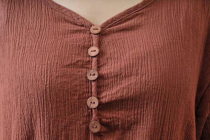 Close-up of a textured rust-colored dress with buttons, showcasing a stylish and casual design for spring and autumn.