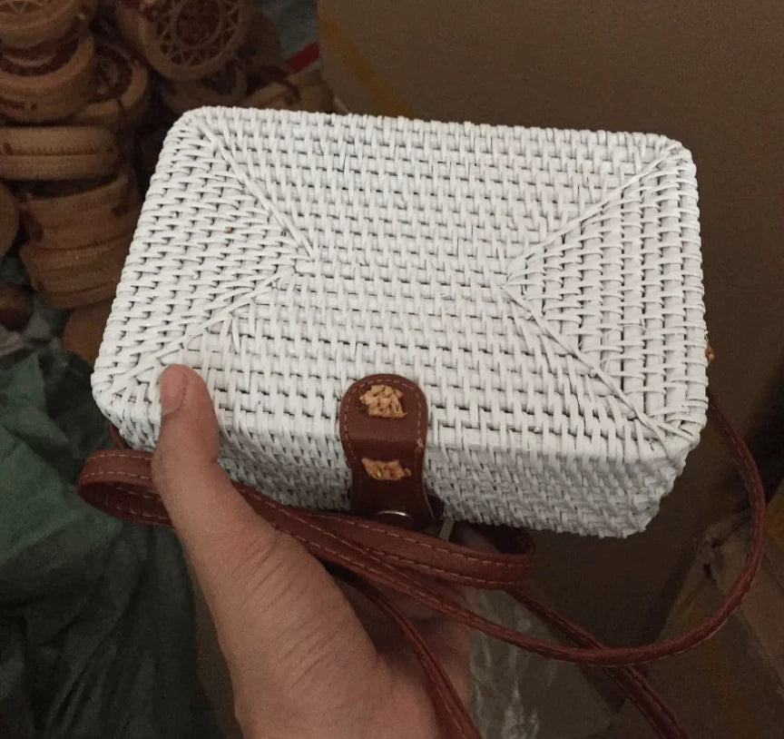 Woven rattan mini bag with leather closure, showcasing white straw weaving and a vintage style in hand.