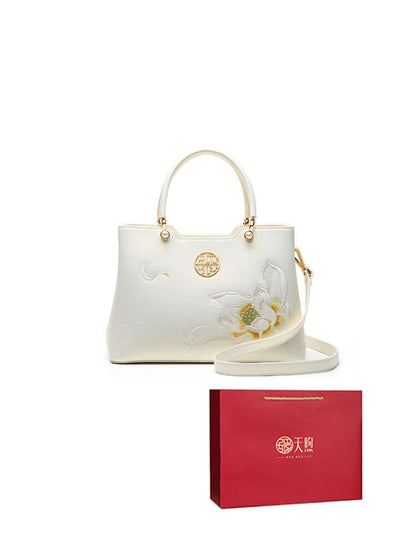 Pearl cowhide handbag with elegant floral design, accompanied by a stylish red gift bag.