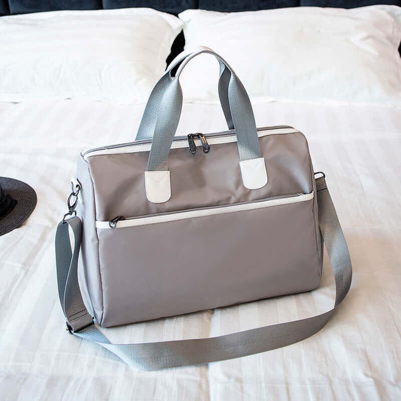 Hand-held large-capacity men's and women's body bags in gray displayed on a bed.