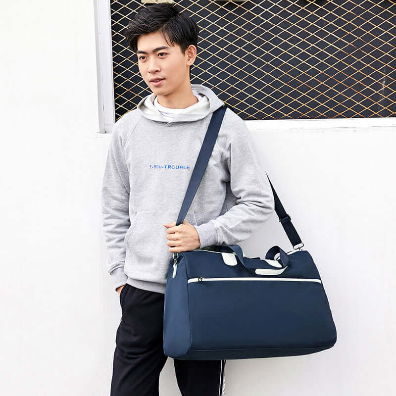 Hand-held large-capacity men's and women's body bags being carried by a young man in casual attire.