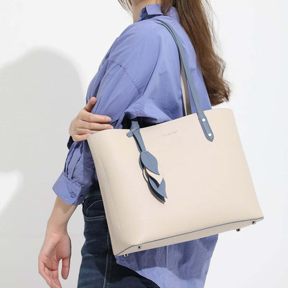 Woman carrying a large capacity leather handbag, showcasing its minimalist design and elegant features.