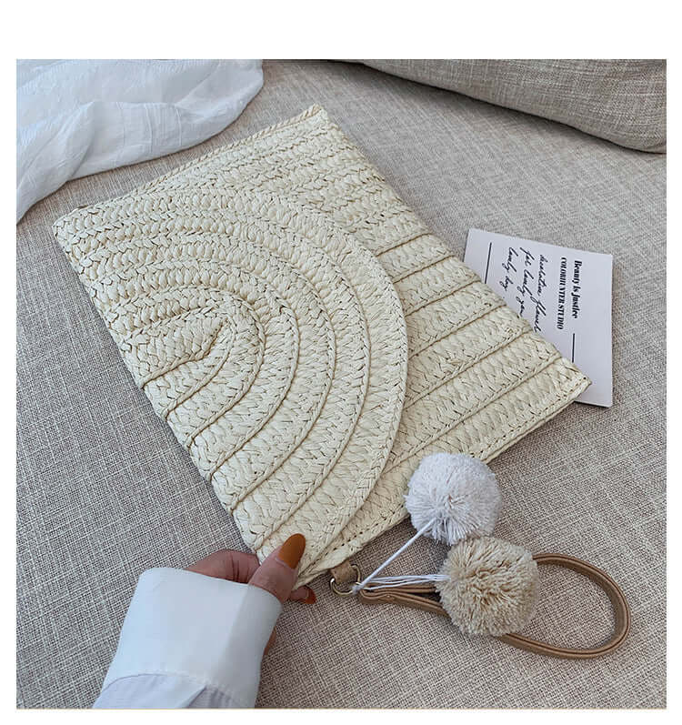 New style hand woven bags in summer shown on a table with pom pom accessory and white fabric.