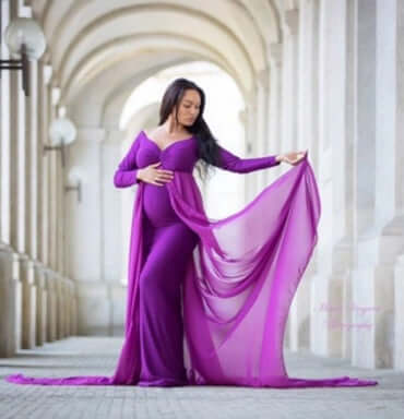 Pregnant woman cloak dress showcasing a woman in a flowing purple chiffon gown during pregnancy.