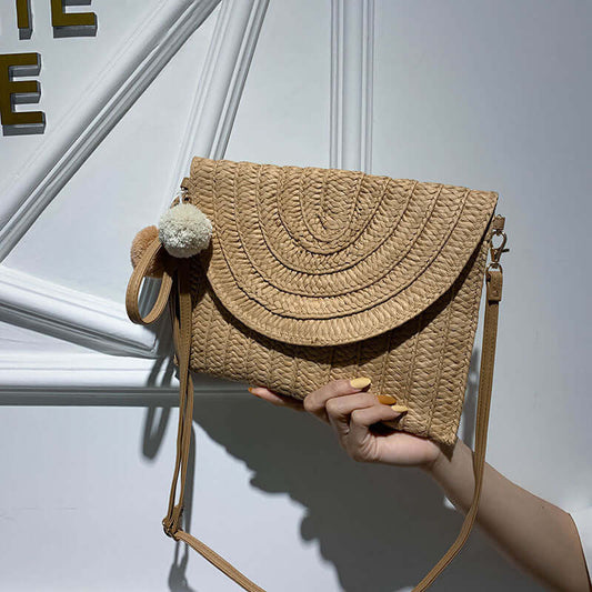New style hand woven bags in summer, stylish beige handwoven clutch with adjustable strap and pom-pom detail.