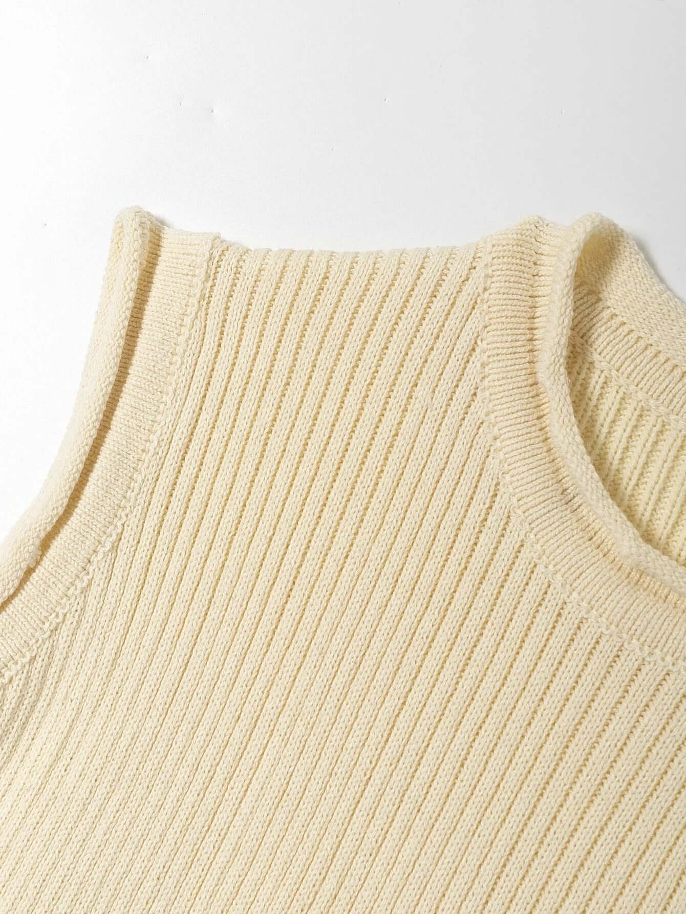 Knitwear top vest woman, beige knitted fabric, close-up of neckline and texture, solid color, casual pullover style