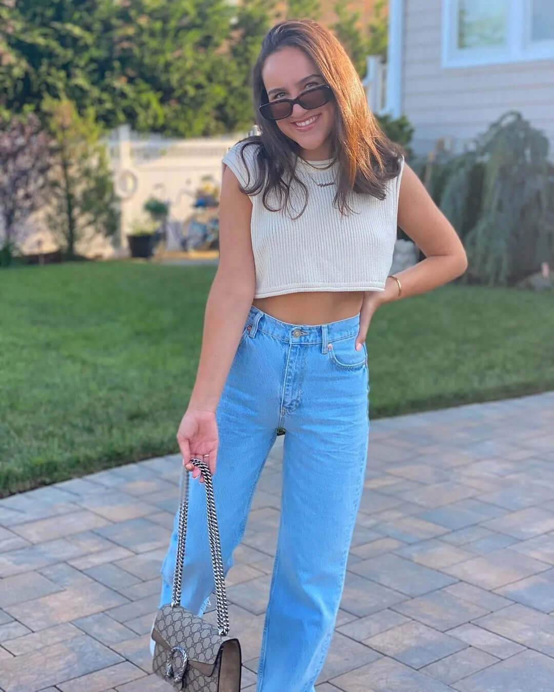 Knitwear top vest woman, cropped style, summer outfit, casual look, featuring light-colored top and light blue jeans.
