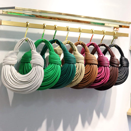 womens woven microfiber leather handbag in various colors displayed on hooks