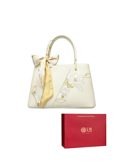 Pearl cowhide handbag with floral design and ribbon, paired with elegant gift packaging.