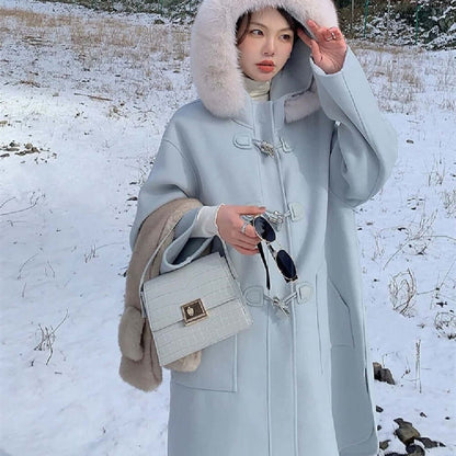 Woman in a light blue coat with fur hood holding a Crocodile-Pattern Leather Handbag – Versatile Carry in a snowy landscape.