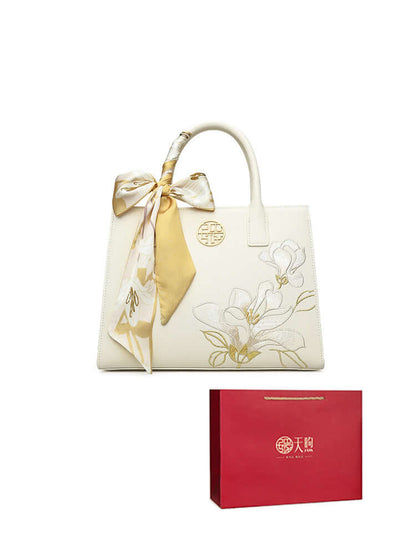 Pearl cowhide handbag with elegant floral design and silk ribbon, packaged in a stylish gift box.