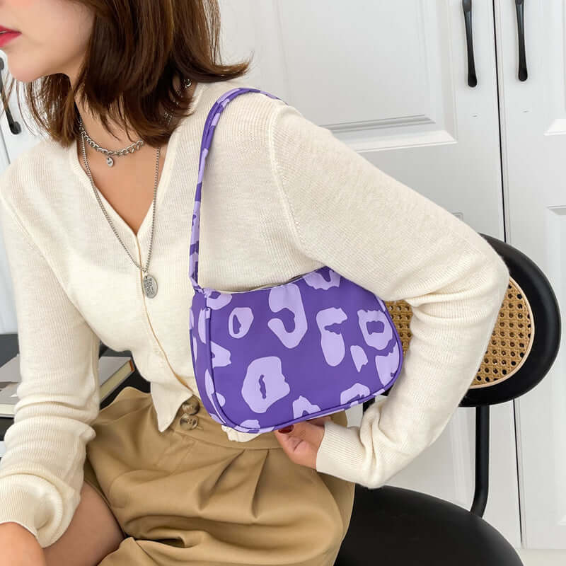 Korean Street Trend Hand-carried Women's Bags in purple leopard print being held by a woman wearing a cream sweater.