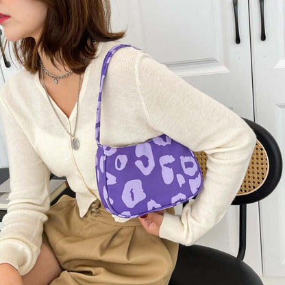 Korean Street Trend Hand-carried Women's Bags in purple leopard print being held by a woman wearing a cream sweater.